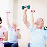 Shot of a group of smiling seniors sitting on swiss balls and lifting weights in an exercise class